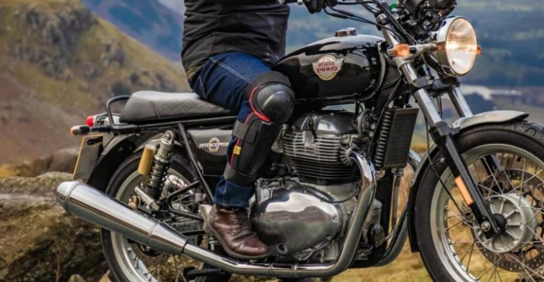 Man sitting on Royal Enfield bike wearing external knee guards